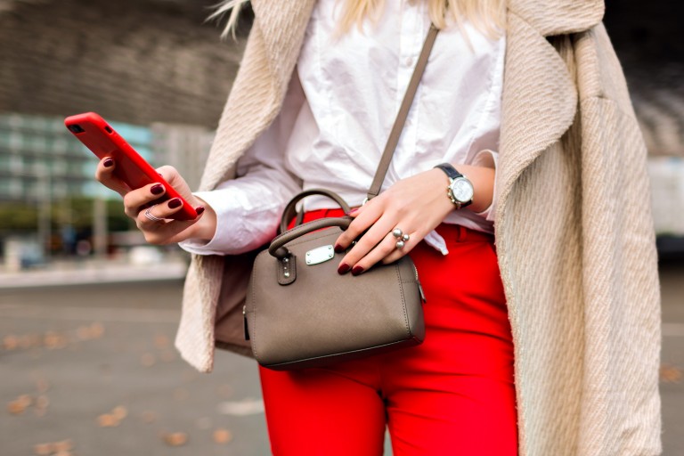 close up fashion details you business woman tapped something on her phone urban autumn city background bright suit and cashmere coat ready for conference